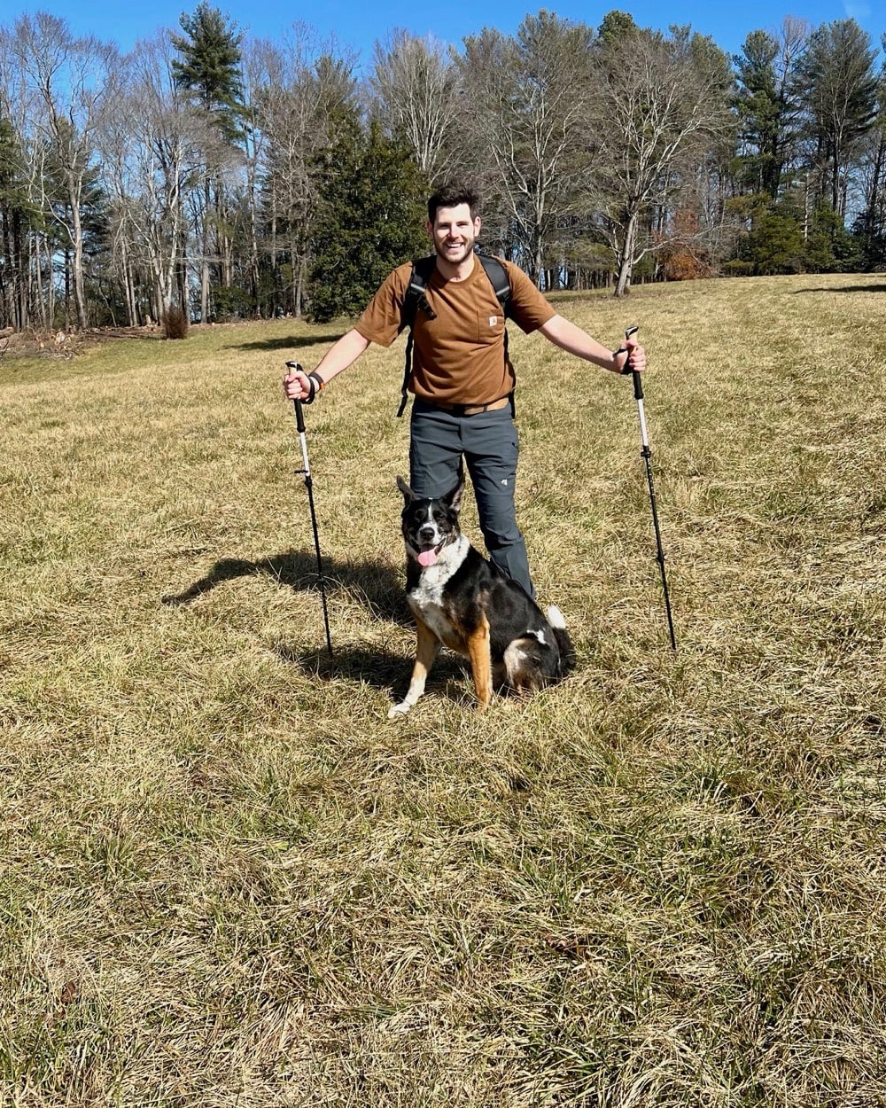 William Dugal hiking with trekking poles and his dog after recovery